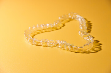 Transparent dental aligners on a colored yellow background, close-up, side view. Modern methods to...