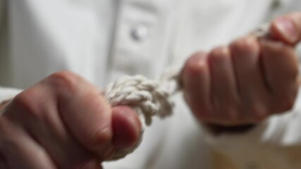 A strong man tries to break and stretch a thick rope.
A strong rope in the hands of a man.
A strong rope close-up. In the hands of a guy