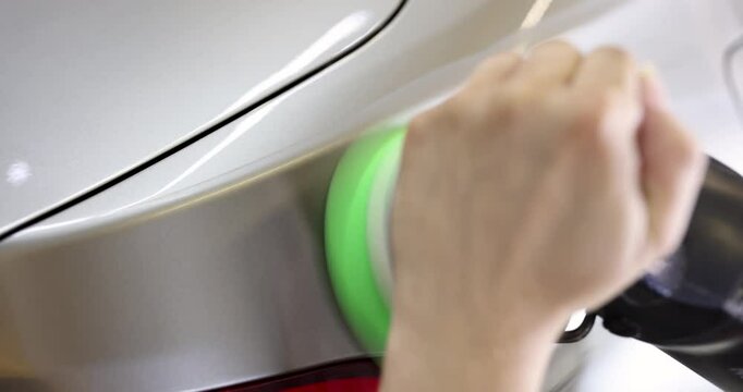 Worker uses orbital polisher with foam pad. Technician moves polisher in slow circular motions to ensure even coverage and high-gloss finish of car