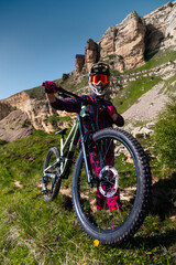 Athlete rider in bicycle helmet on his bike standing and resting before descent in mountains...
