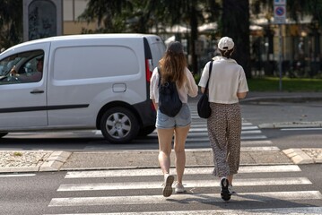 Two young women cross the street.