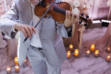A male violinist plays a classical musical instrument, the violin, at a wedding.