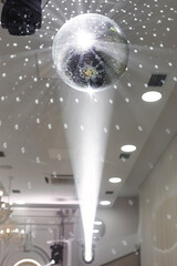 Shiny silver disco ball hanging from the ceiling, illuminated by a spotlight.