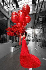 Young woman in a red dress with large helium balls.