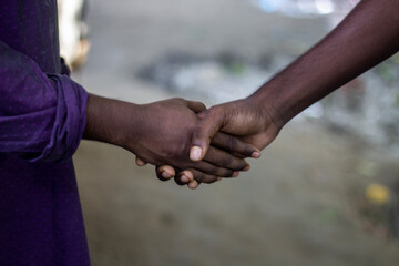Two black people are shaking hands, and the background is blurred