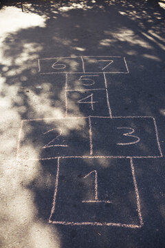 Hand drawn hop scotch game on asphalt road playground