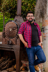 An oversized man with a black beard and hair and glasses using an antique mechanism in a colonial...