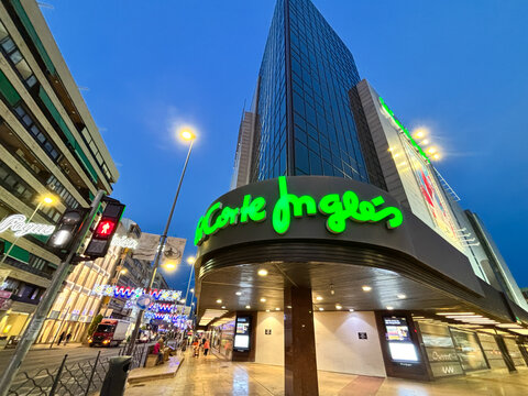 Alicante, Spain - June 24, 2025: El Corte Ingles department store illuminated at dusk, showcasing modern architecture and vibrant city life in a bustling urban environment