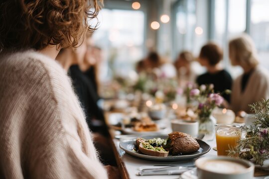 A warm, inviting cafe scene with people enjoying a communal breakfast. Fresh flowers and delicious pastries adorn the table.