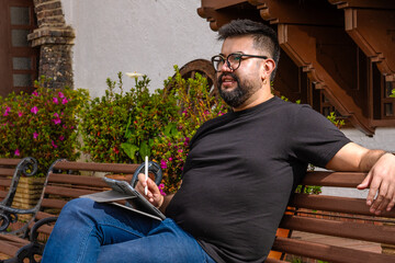 Latino man working remotely on a tablet from a colonial town in Colombia. Concepts of remote work,...