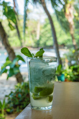 Mojito cocktail with mint and lime on tropical beachside table