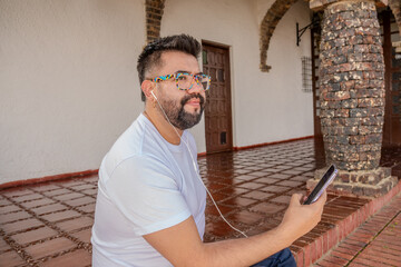 A college student listening to music on his cell phone in the university's colonial-style hallway....