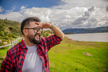 Hipster Latino man in a red striped shirt, impressed by Lake Guatavita. Concepts of emotions,...