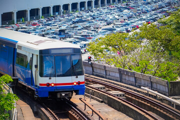 Obraz premium Electric metro train on a turn from a depot against the backdrop of a huge car park, transport system