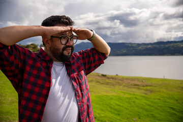 Hipster Latino man in a red striped shirt, impressed by Lake Guatavita. Concepts of emotions,...
