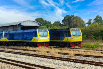 Head diesel locomotive side view of the station platform and commuter train in the parking lot.