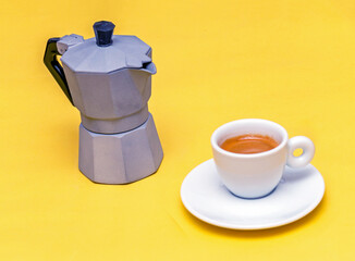 Traditional Italian retro metal coffee pot next to espresso in a ceramic cup