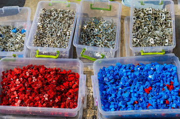 Colorful plastic and metal eyelets cable connectors piles in plastic boxes outside on market