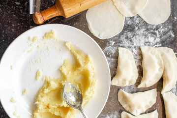 Cooking dumplings and vareniki with potato filling from dough on the kitchen countertop. Home cooking