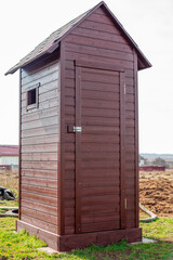 Wooden country new toilet with a roof and a window on the street. Toilet installation