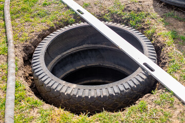 A pit for an outdoor village toilet with walls made of rubber tires. Making a toilet on a personal plot