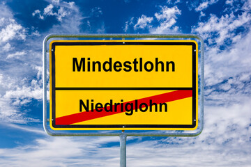 Ein Ortsschild ist symbolich beschriftet mit Niedriglohn zum Mindestlohn - FOTOMONTAGE