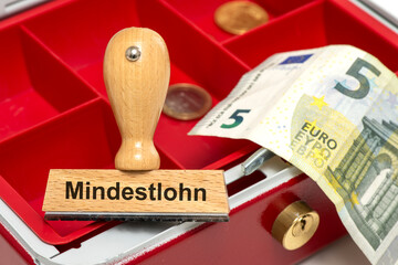 Ein Holzstempel ist beschriftet mit dem Aufdruck Mindestlohn