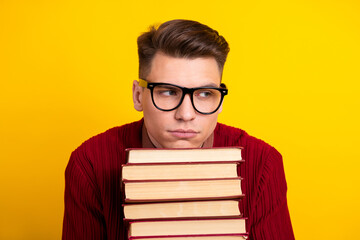 Handsome Young Male Student Holding book with Thoughtful Expression on Yellow Background