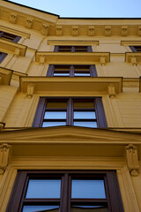 Classic building facade. Detailed window frames. Cream-colored walls. Blue sky reflection. Historic architecture, ornamental design, urban scenery, heritage building exterior.

