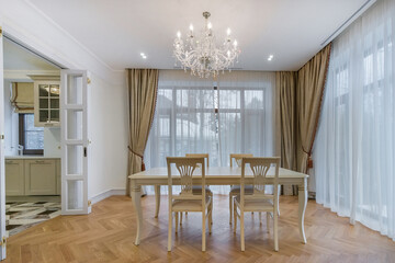An elegant dining area with a chandelier and large windows providing natural light in a modern...
