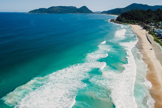 Beach and ocean with surfing waves in Brazil. Drone view of Campeche beach in Floripa