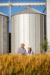 Thai Female Worker and Senior Male Using Smartphone in Front of Silos in Wheat © Mediteraneo