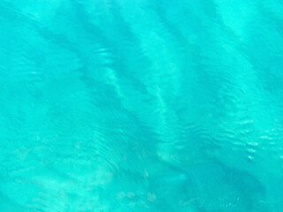 A stunning view of the blue expanse of sea water in Calabria, Italy, where the deep turquoise and sapphire tones of the Tyrrhenian Sea stretch to the horizon. The sunlight dances on the gentle waves