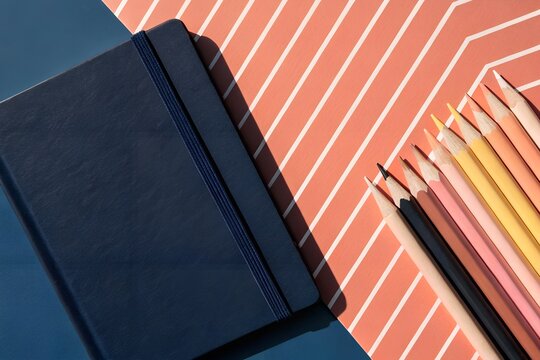 Stack of notebooks and books with office items on a black background