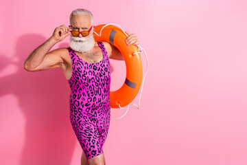 Photo of serious old man touch sunglass look hold lifebuoy for rescue wear swimsuit isolated pastel color background