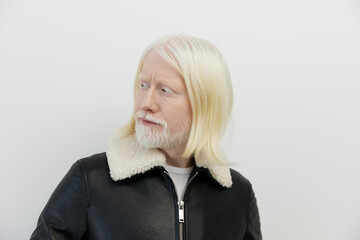Portrait of an older man with white hair and beard, wearing a black leather jacket with a white...