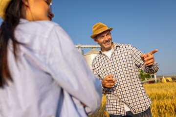  Two Silo Workers Standing in Wheat Field Discussing Future Tasks