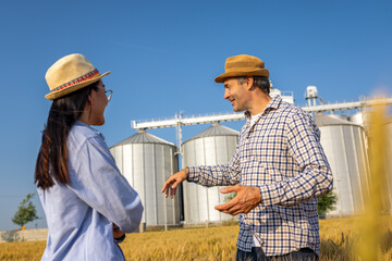  Two Silo Workers Standing in Wheat Field Discussing Future Tasks