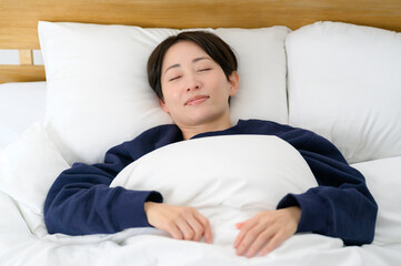 朝の光の中で目を閉じてベッドに横たわる女性のリラックスした寝顔