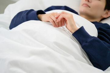 クローズアップで捉えた布団の中の女性の穏やかな寝顔が印象的な一枚