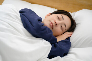 布団に顔を埋めて安らかに眠る女性が穏やかな時間を過ごすシーン