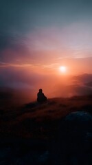Lone figure meditating on a hilltop at sunrise
