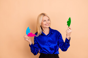 Smiling woman holding colorful puzzle pieces wearing blue shirt against beige backdrop, symbolizing...
