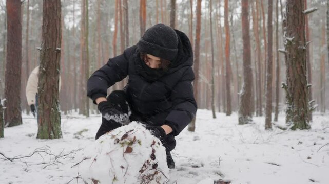A diligent young boy concentrates on his task, showing perseverance as he rolls a snowball. This demonstrates the snowball effect, where consistent effort leads to compounding growth and results.
