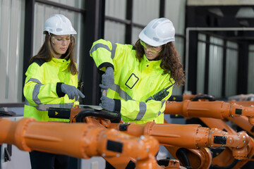 Two engineers work  in a  robotic arm manufacturing facility