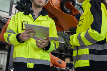Two engineers work  in a  robotic arm manufacturing facility