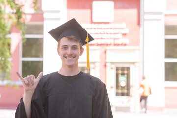 Caucasian young man in graduation gown communicating using sign language. 