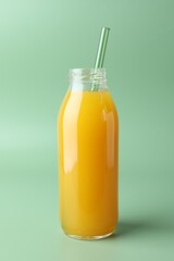 Tasty mango juice in glass bottle on green background