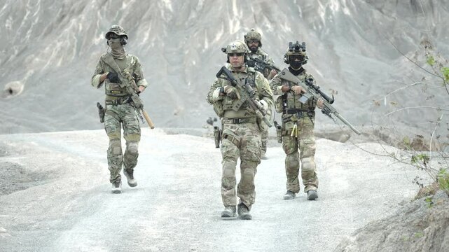 A special forces squad on patrol carefully navigates steep and difficult terrain in a barren mountainous region A concept for mountain warfare and endurance