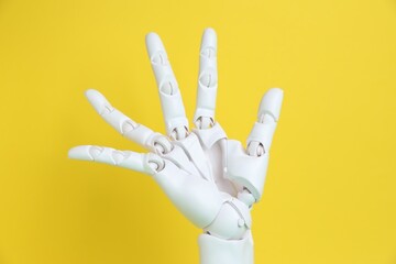 One white mannequin hand on yellow background